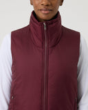 Person wearing a maroon puffer vest over a white shirt on a light gray background