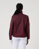 Person wearing a maroon jacket on a plain background