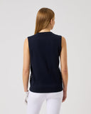 Woman wearing a black sleeveless top and white pants on a light gray background