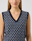 Woman wearing a sleeveless patterned top against a plain background