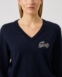 Person wearing a navy blue sweater with a logo on a light gray background
