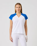 Woman wearing a white and blue top with white pants on a light gray background