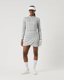 Person wearing a patterned dress and visor on a white background