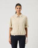 Woman wearing a beige short-sleeve shirt and black pants on a white background