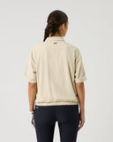 Person wearing a beige shirt and dark pants on a light gray background