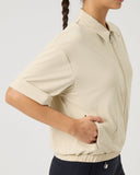 Person wearing a beige short-sleeve shirt on a plain background