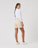 Person wearing a white shirt and beige shorts on a plain background