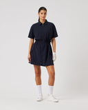 Woman wearing a navy dress with white shoes and socks on a light gray background