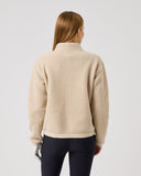 Person wearing a beige fleece jacket on a plain background