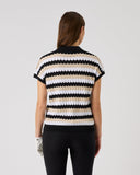 Woman wearing a striped black, white, and beige sweater on a plain background