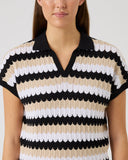 Woman wearing a striped shirt with black, white, and beige colors on a plain background
