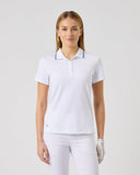 Woman wearing a white polo shirt and pants on a light gray background