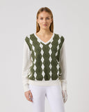 Woman wearing a green and white patterned sweater vest on a plain background