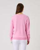 Person wearing a pink sweater and white pants on a light gray background