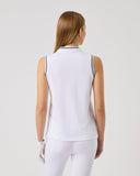 Woman wearing a white sleeveless top and pants on a light gray background