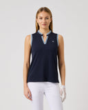 Woman wearing a navy sleeveless top with white pants on a light gray background