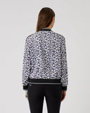 Person wearing a black and white patterned bomber jacket on a light gray background