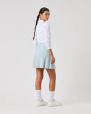 Person wearing a white long-sleeve shirt and checkered skirt on a plain background