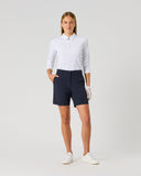 Woman wearing a white shirt and navy shorts on a light gray background