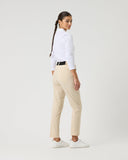 Woman wearing a white shirt and beige pants on a plain background