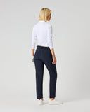 Woman wearing a white shirt and navy pants on a plain background