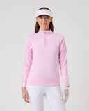 Woman wearing a pink long-sleeve top, white pants, and a white visor on a light gray background