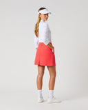 Daily Sports Woven Poppy Red Skort in poppy red – women's A-line woven golf skort showing back kick pleat, structured waistband and clean tailored fit, three-quarter back view on model styled with white 3/4 sleeve polo and white viso