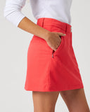 Daily Sports Woven Poppy Red Skort close-up of poppy red woven fabric with structured waistband, silver logo button, angled side pocket and zip security pocket detail, side view