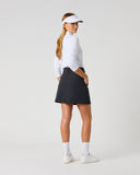 Daily Sports Woven Black Skort in black – women's A-line woven golf skort showing back kick pleat, structured waistband and clean tailored fit, three-quarter back view on model styled with white 3/4 sleeve polo and white viso