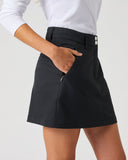 Daily Sports Woven Black Skort close-up of black woven fabric with structured waistband, silver double-button closure, angled side pocket and zip security pocket detail, side view