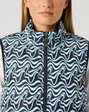 Close-up of women's dark navy flair motion wave print reversible golf vest with full zip, stand-up collar, and mint accent detail
