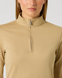 A close-up of a model wearing a beige long-sleeve quarter-zip pullover top against a light gray studio background.
