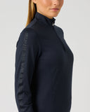 A woman shown in side profile wearing a dark navy athletic quarter-zip pullover with textured vertical detailing on the sleeve, against a light gray studio background.
