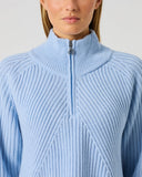 Close-up of women's light blue ribbed wool blend golf pullover with half zip, high collar, and Daily Sports branded silver zipper pull
