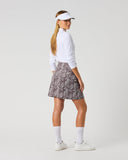 Daily Sports Dull Zebra Printed Skort in muted brown and white abstract zebra swirl print – women's A-line golf skort showing all-over print back panel and flared hem, three-quarter back view on model styled with white long sleeve polo and visor