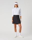 Daily Sports Black Ribbed Skort in black – women's smooth A-line golf skort with high elasticated waistband and built-in shorts, full length front view on model styled with white long sleeve polo and viso