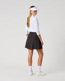 Daily Sports Black Ribbed Skort in black – women's smooth A-line golf skort showing clean flared back panel and tailored fit, three-quarter back view on model styled with white long sleeve polo and viso