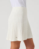 Daily Sports Madelene White Cable Knit Skort close-up of cream ivory vertical cable-knit texture with flared pleated hem and silver logo pin detail, side view