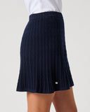 Daily Sports Madelene Dark Navy Cable Knit Skort close-up of deep navy vertical cable-knit texture with flared pleated hem, elasticated waistband and silver logo pin detail, side view