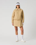 Women's camel quilted golf skirt styled with matching quilted jacket and white visor – full outfit front view
