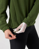 Close-up of women's khaki green mid-layer golf top showing adjustable drawcord hem with toggle and ribbed cuff detail
