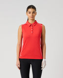 Daily Sports Poppy Red Piping Sleeveless Polo in bold poppy red – women's sleeveless golf polo with white contrast piping along shoulders and side seams, classic collar and white button placket, front view on model styled with black trousers and golf glove