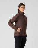A woman modeling a brown quilted zip-up jacket against a light gray studio background.