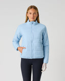 A woman modeling a light blue quilted zip-up jacket against a plain light gray studio background.