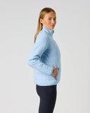 A woman modeling a light blue puffer jacket with a high collar, shown from a side profile against a plain light gray studio background.