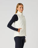A woman modeling a white quilted sleeveless puffer vest over a navy long-sleeve athletic top and navy leggings, standing against a light gray studio background.