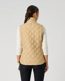 A woman shown from the back wearing a beige quilted vest over a white long-sleeve top and black pants, photographed against a plain light gray studio background.