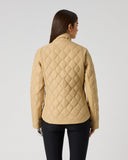 A woman viewed from the back wearing a quilted beige jacket and black pants against a plain light gray studio background.