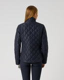A woman viewed from the back wearing a dark navy quilted jacket and matching dark pants against a plain light gray studio background.