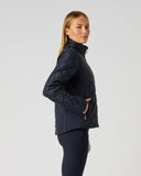 A woman modeling a dark navy quilted puffer jacket, shown in profile against a solid light gray studio background.